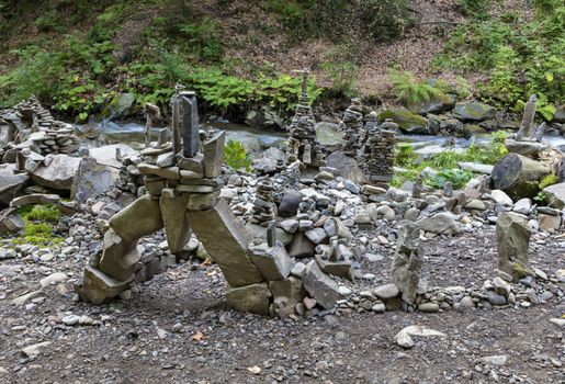 Balancing stones on the bank of a mountain river in the Carpathians. Towers, pyramids and sculptures from river pebbles on the banks of the stream.