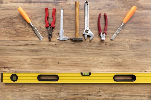 Old construction tools pliers, calipers, hammer, adjustable wrench, chisel, nippersare, llevel ocated vertically on the wooden floor close-up