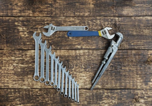 Set of combination wrenches and old adjustable wrenches on an old wooden boards background