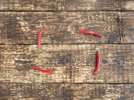 Red hot chili peppers on old wooden table with place for text