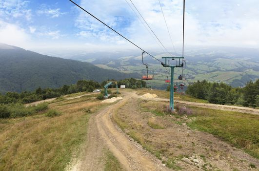 The mountain lift carries tourists and luggage up and down the mountains against the backdrop of the summer mountain scenery in the Carpathians