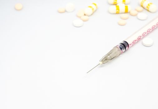 Syringe, injection needle and some pill on white background