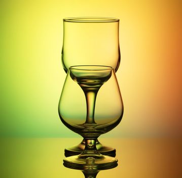 glasses for wine and cognac with a thin contour stand arches after the other, on a bright yellow-green background