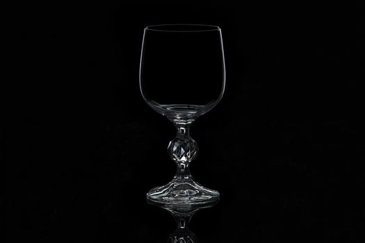 glass for wine with a thin contour and curly leg, isolated on a black background