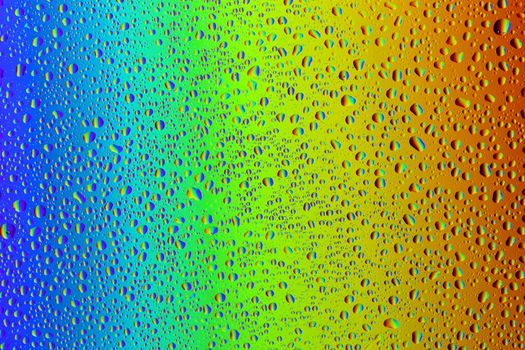 Drops of water against the background of the rainbow and with its reflection in them