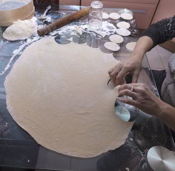 The woman rolled out the dough and made blanks for dumplings and vareniks