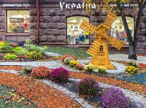 Kiev, Ukraine - October 2017: a flowerbed and wooden mill in front of the entrance to the store Ukraine in the center of Kiev
