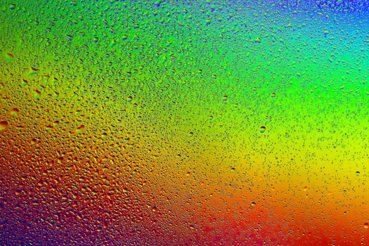 Drops of water against the background of the rainbow and with its reflection in them