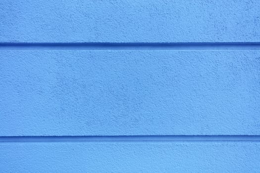 Concrete wall texture with colored bright blueplaster. Construction coat-plaster made of insulated material on the wall with horizontal dividing grooves.