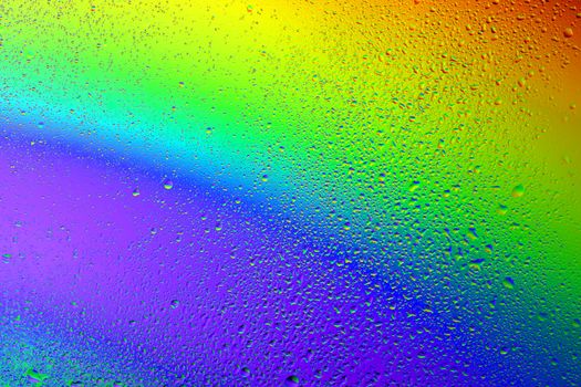 Drops of water against the background of the rainbow and with its reflection in them
