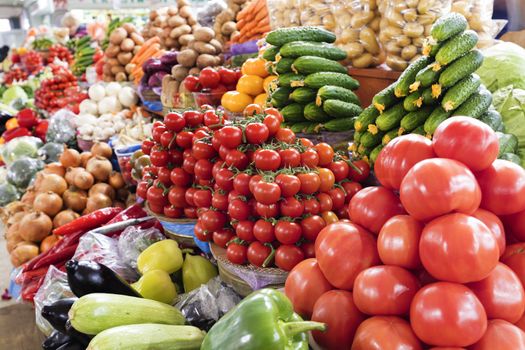 branches of cherry tomatoes, cucumbers, peppers, eggplants, onions, cabbage, zucchini and other vegetables for sale on the market