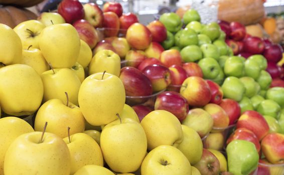 bright yellow apples of Golden variety and other varieties of apples lie on the counter for sale on the market