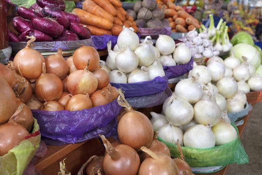 different varieties of onions and other vegetables for sale on the market