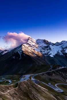 Dramatic Sunset at Snowy Mountains Peaks and High Alpine Road.