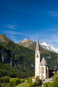 Pitcuresqe Church in Austria Village. High Alps Mountains in Background.