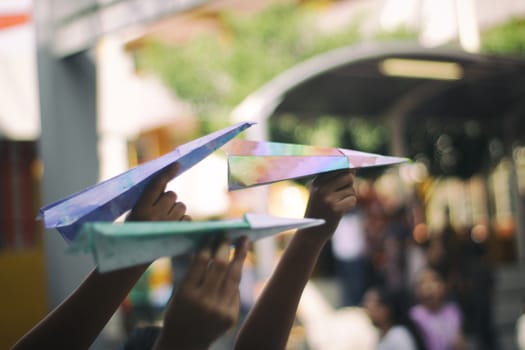 Photograph of some paper colorful planes on ready to fly on children hands