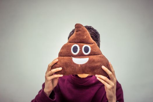 Photograph of a man with poop emoji cushion