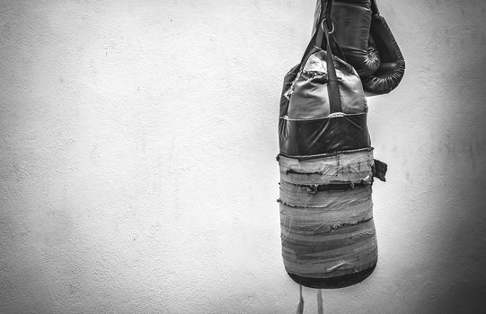 Photograph of an old punching bag and a pair of boxing gloves