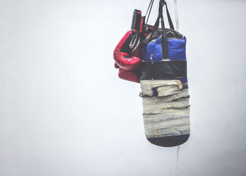 Photograph of an old punching bag and a pair of boxing gloves