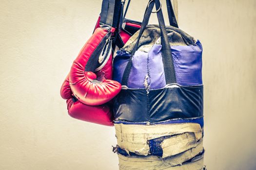 Photograph of an old punching bag and a pair of boxing gloves