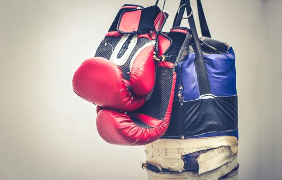 Photograph of an old punching bag and a pair of boxing gloves