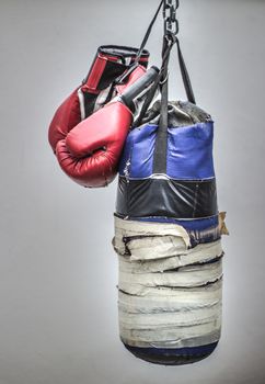 Photograph of an old punching bag and a pair of boxing gloves