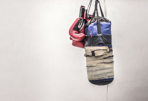 Photograph of an old punching bag and a pair of boxing gloves