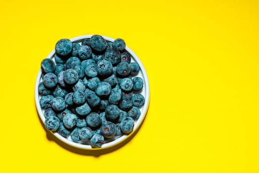 Market Fresh Blueberry on Vibrant Yellow Background. Food Background with Copy Space. Top View
