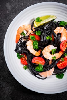 Squid Ink Pasta with Prawns , Tomatoes, Lemon and Herbs. Black Spaghetti, Black Organic Noodles . Mediterranean Gourmet Food.