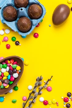 Colorful Easter BAckground. Chocolate Eggs and Candy on Yellow Background. Copy Space on Flat Lay Design.