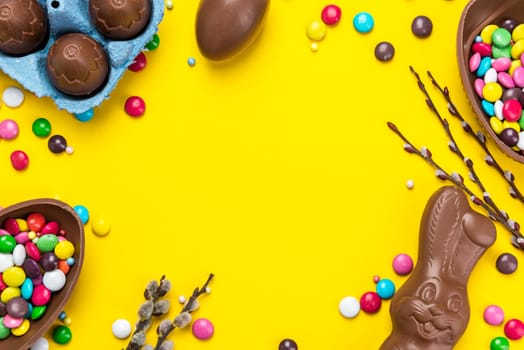 Colorful Easter BAckground. Chocolate Eggs and Candy on Yellow Background. Copy Space on Flat Lay Design.