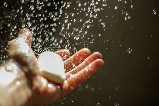 Photograph of an open human hand with soap under water drops