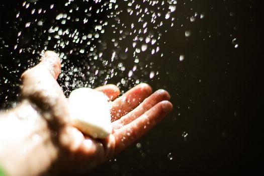 Photograph of an open human hand with soap under water drops