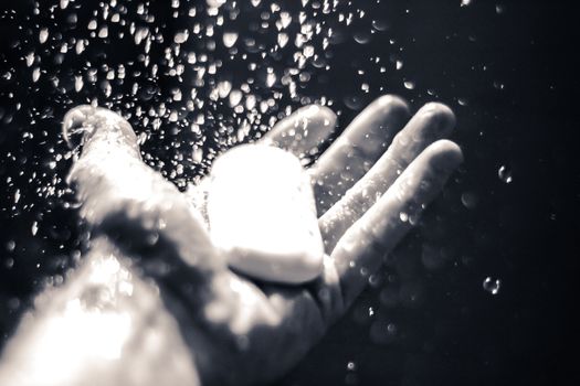 Photograph of an open human hand with soap under water drops