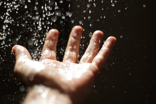 Photograph of an open human hand under water drops