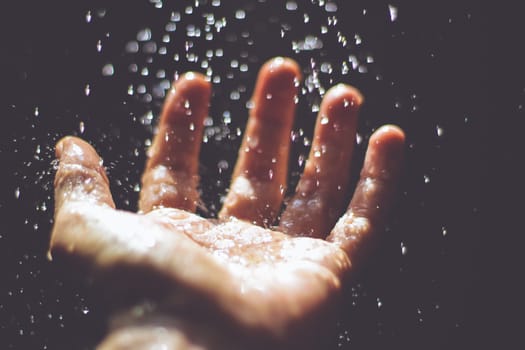 Photograph of an open human hand under water drops