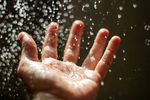 Photograph of an open human hand under water drops