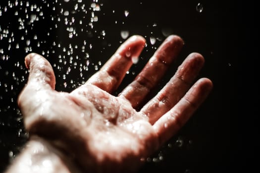 Photograph of an open human hand under water drops