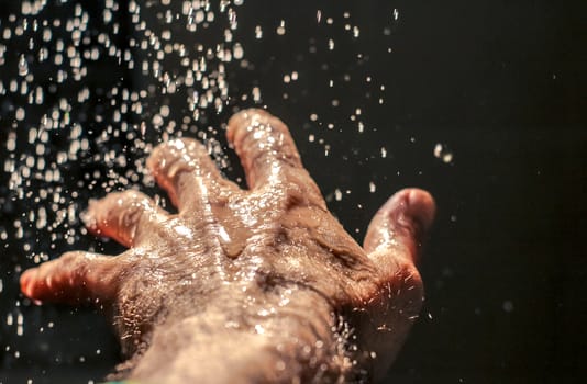 Photograph of an open human hand under water drops