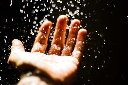 Photograph of an open human hand under water drops