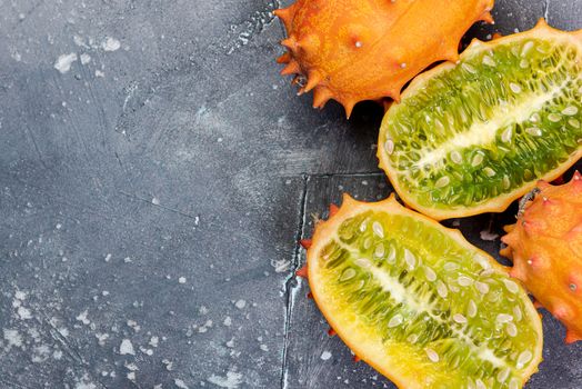 Whole and Cut Kiwano or Horned Melon Exotic Fruit on Concrete Border Background.