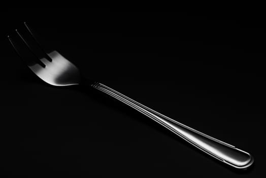 One Silver or Stainless Steel Fork. Close Up Detail view. Dark Background. Low Key Image.