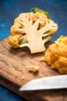 Yellow Cauliflower Cabbage on Cutting Board. Market Fresh Organic Food. Plant Based Diet.