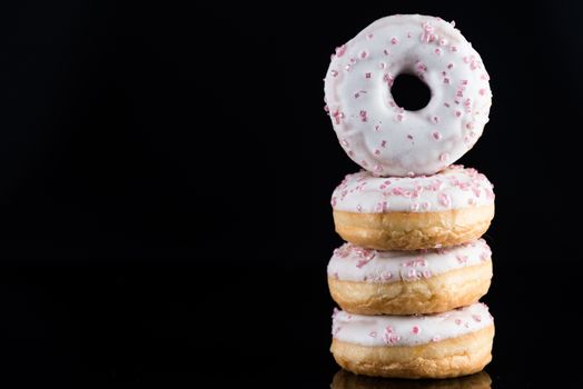 White Chocolate Donuts or Doughnuts Tower on Dark Background. Copy Space for Text.