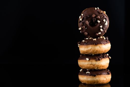 Chocolate Donuts or Doughnuts Tower on Dark Background. Copy Space for Text.