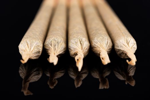 Cannabis Marijuana Rolled in Joints on Dark Reflective Background.