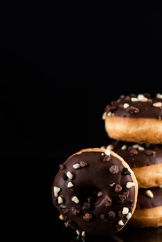 Stack of Chocolate Donuts or Doughnuts on Black Background with Copy Space.