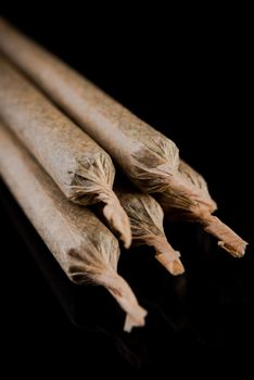 Cannabis Marijuana Rolled in Joints on Dark Reflective Background.
