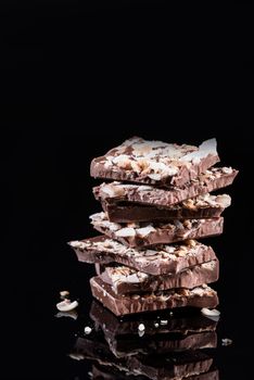 Stack of Broken Chocolate Pieces on Black Background. Copy Space. Closeup View.