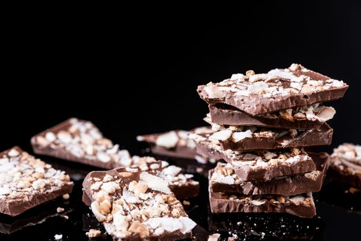 Stack of Broken Chocolate Pieces on Black Background. Copy Space. Closeup View.